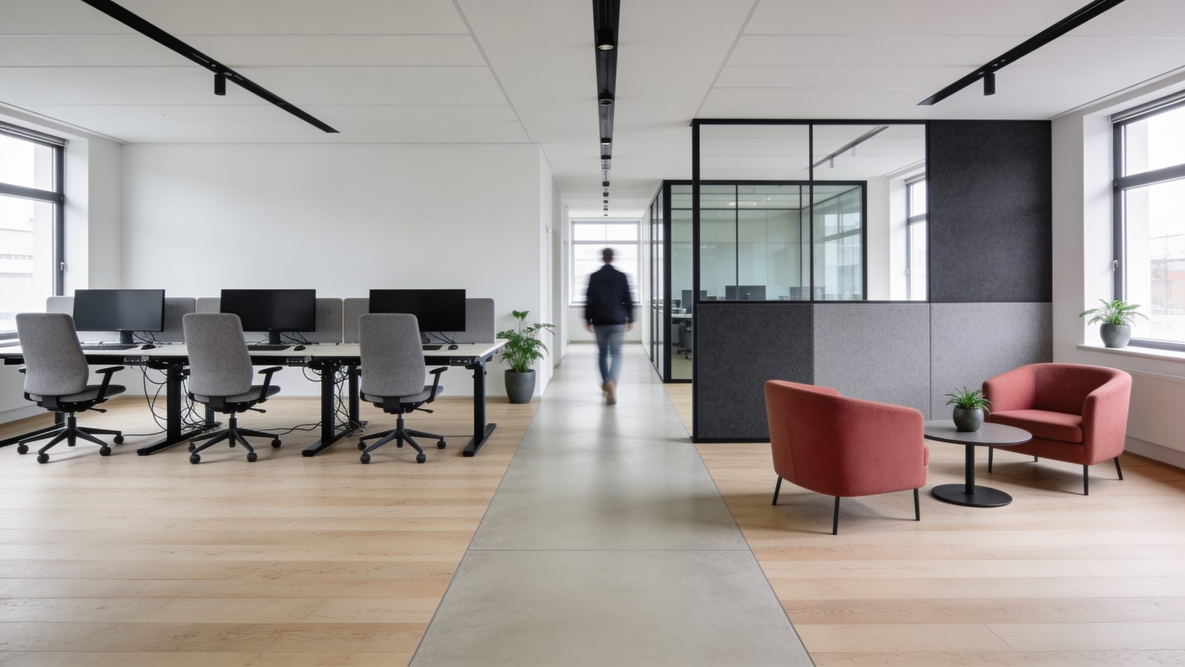 Offene Bürofläche mit einer Reihe höhenverstellbarer Arbeitsplätze links und einer Loungegruppe rechts